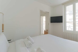 Ein Hotelzimmer mit einem großen Bett, einem an der Wand befestigten Flachbildfernseher und einem Fenster mit Blick nach außen.