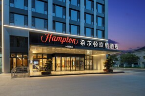 A hotel entrance with a modern facade, illuminated signage, and a welcoming entrance. - Hampton by Hilton Hangzhou Jiubao (Hangzhou)
