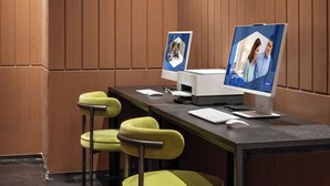 Un espace de bureau moderne comprenant un bureau, deux écrans, un clavier, une souris et deux chaises vertes.