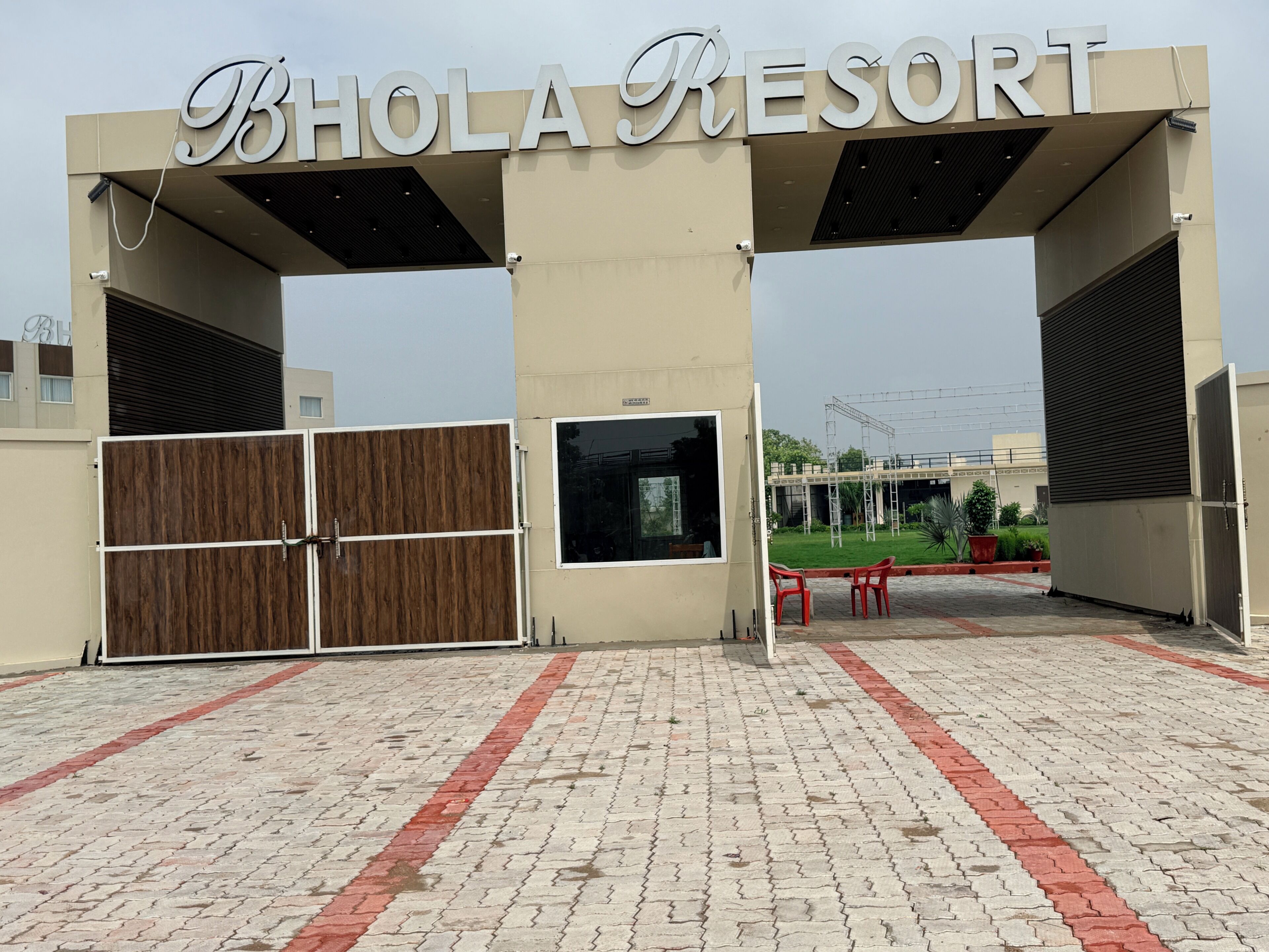 L’entrée du Bhola Resort se distingue par un grand panneau, une porte d’entrée et un chemin pavé.