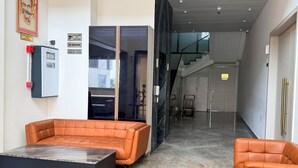 Un vestíbulo moderno con asientos de cuero, un quiosco de registro y una escalera que conduce a los pisos superiores.