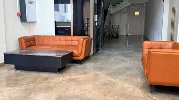 A modern lobby with a leather sofa, a marble coffee table, and a staircase leading to an upper floor.