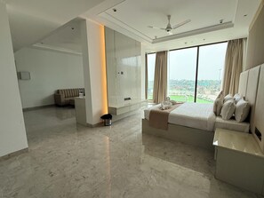Habitación de hotel moderna con una cama grande, zona de estar y vistas a la ciudad.