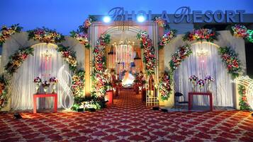 A decorated entrance to a venue with a red carpet, floral arrangements, and a chandelier.
