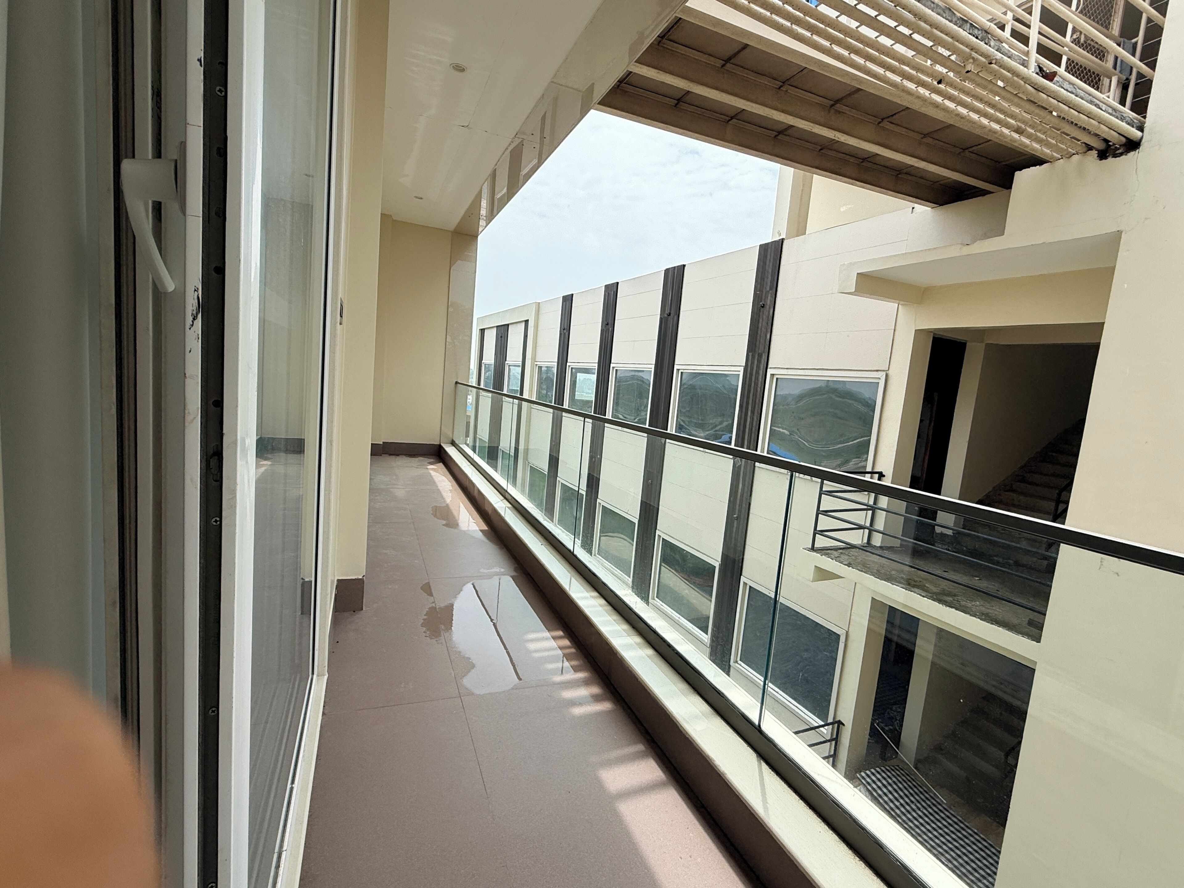 Un pasillo con barandilla de vidrio, una escalera y vistas al exterior.