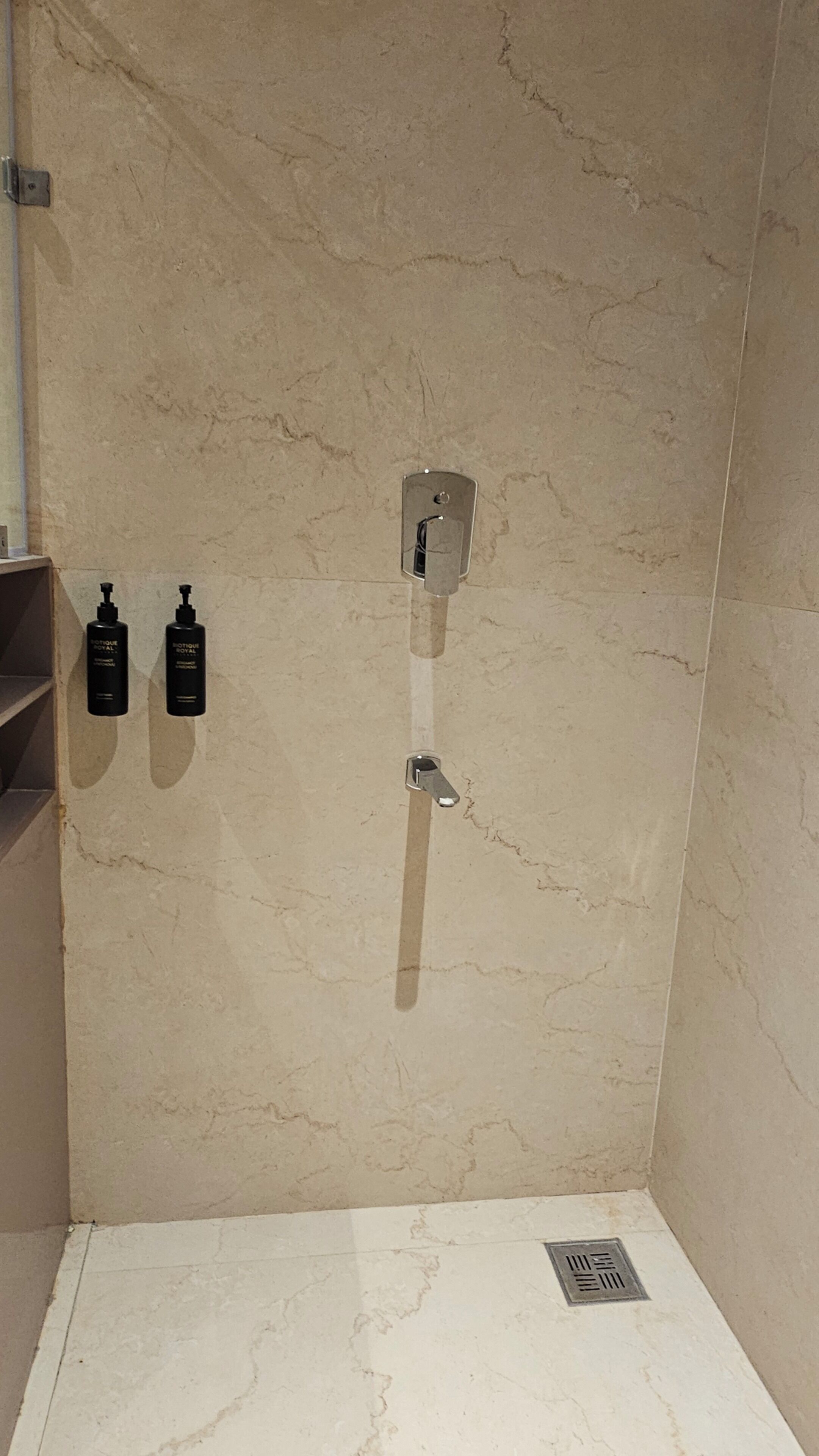 A bathroom with a shower stall, a wall-mounted towel rack, and two bottles of toiletries.