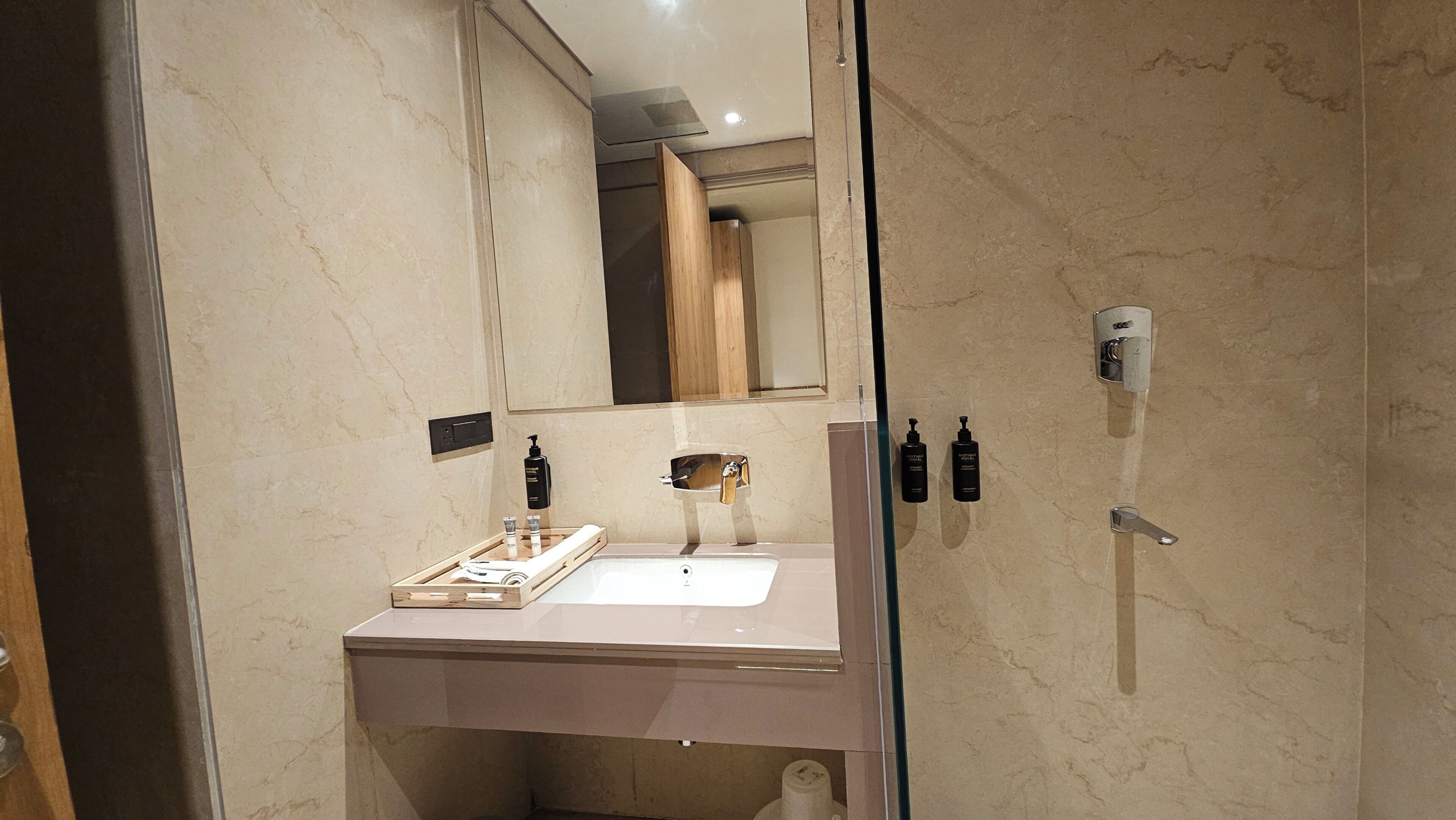 A modern bathroom with a marble countertop, a mirror, and two bottles of shampoo.