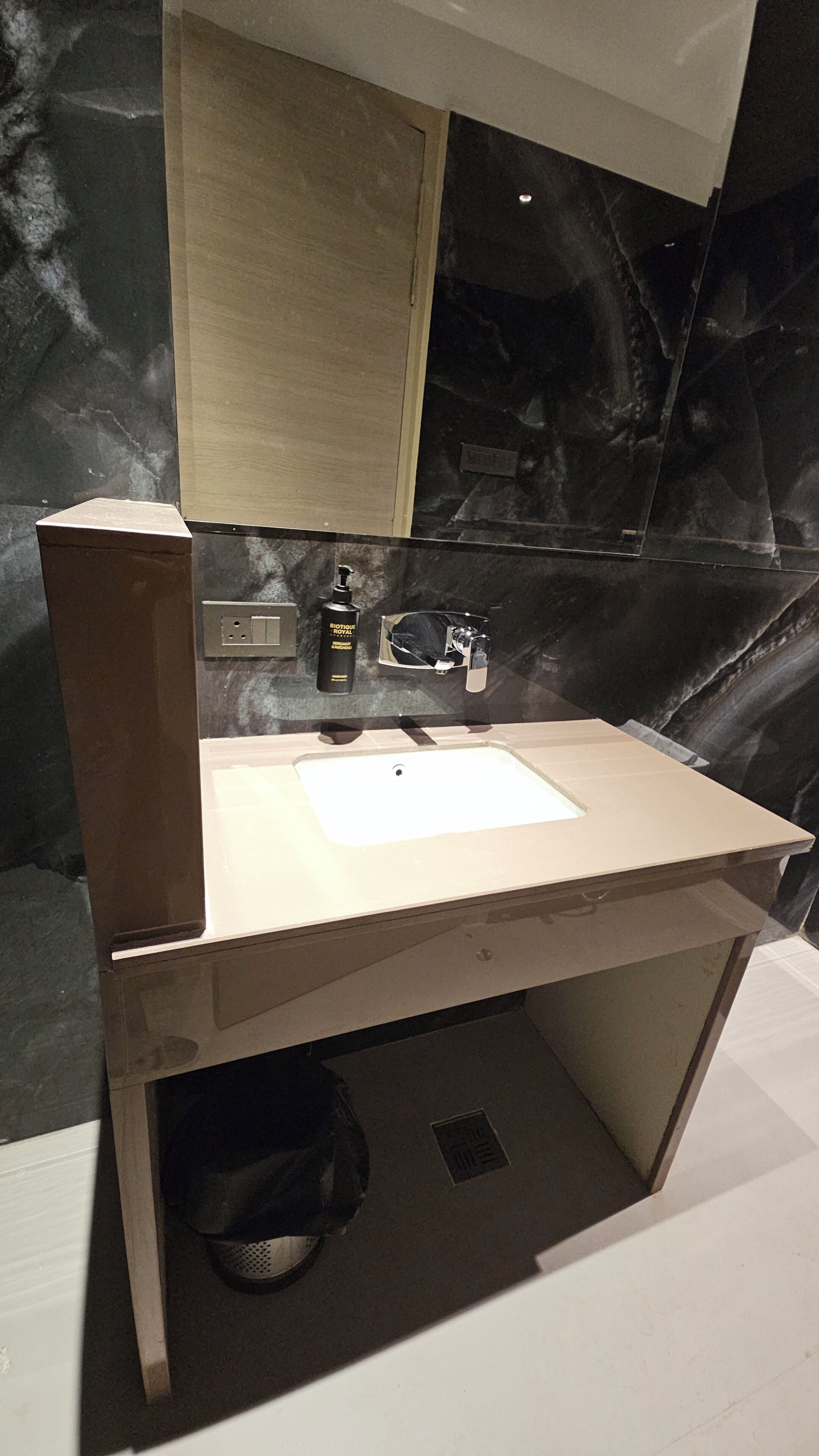 A bathroom with a sink, mirror, and a bottle of hand soap.
