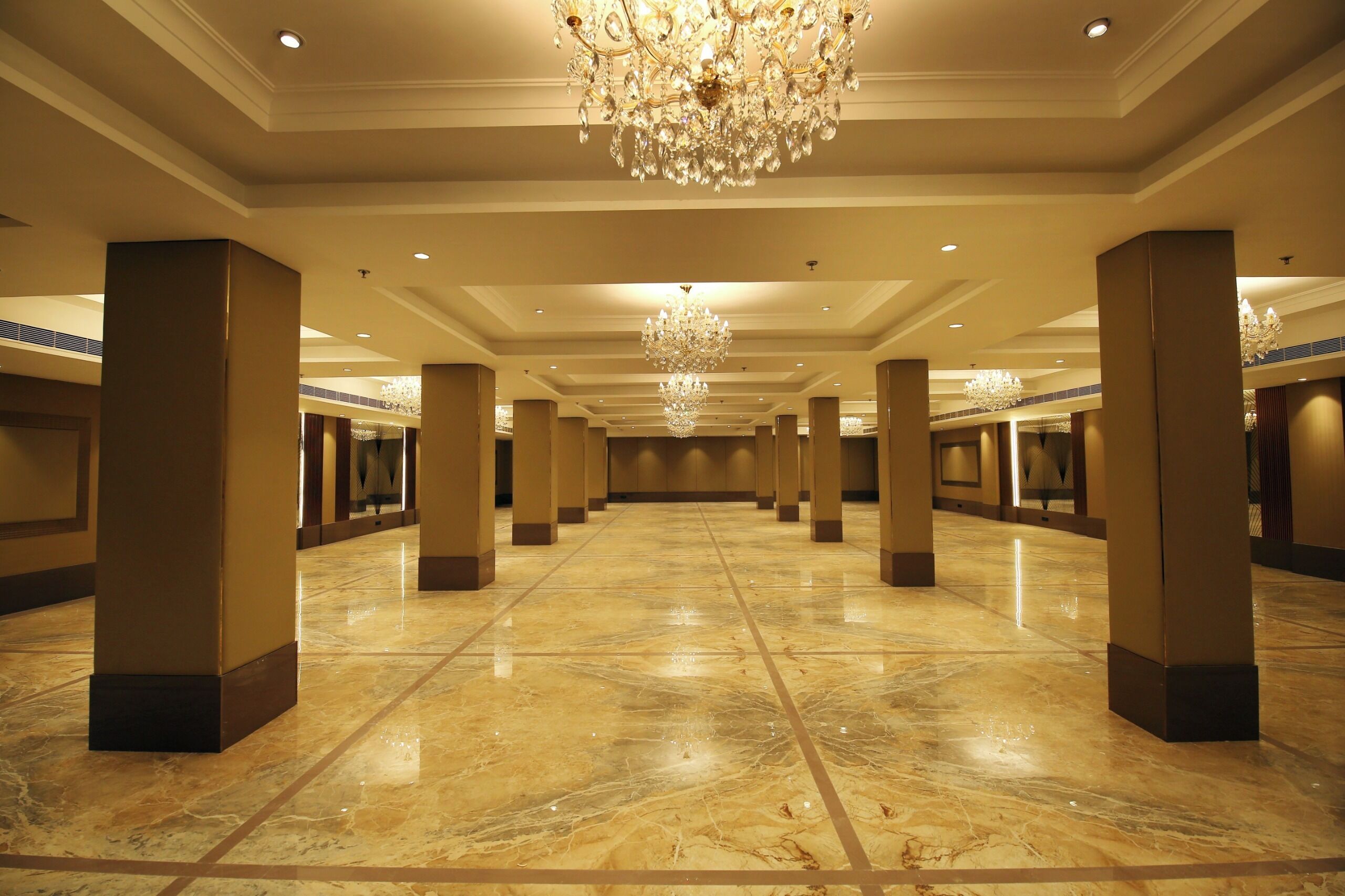 Un hall d’hôtel spacieux, doté d’un sol en marbre, de grandes colonnes et de lustres décoratifs.