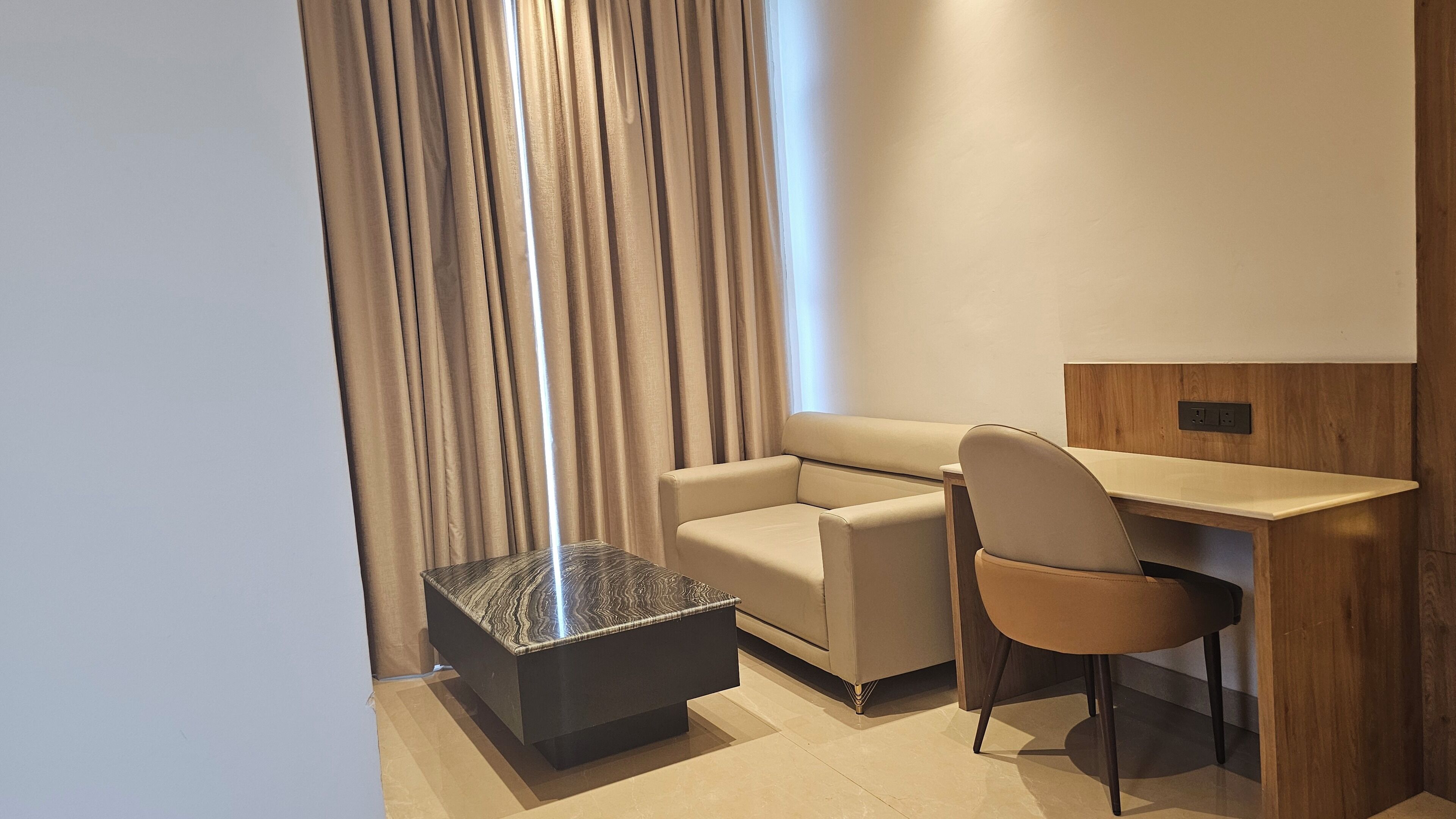 Une chambre d’hôtel moderne équipée d’un canapé, d’un bureau et d’une petite table basse.
