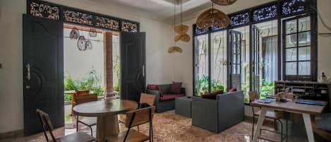 An open-plan living space with a dining area, seating arrangements, and large windows.