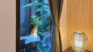 Una habitación con ventana, un armario de madera y una lámpara de mesa.