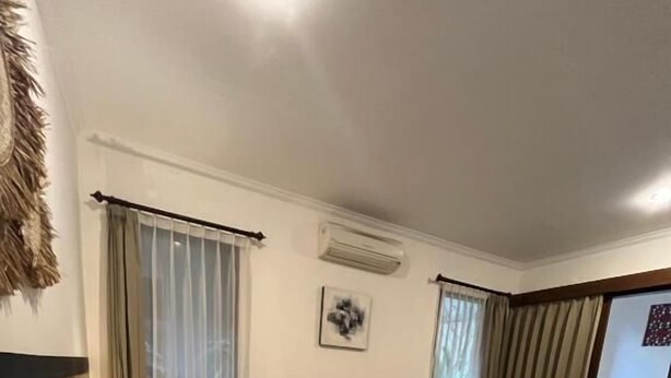 Una habitación de hotel con cama, una silla, una mesita y una ventana con cortinas.