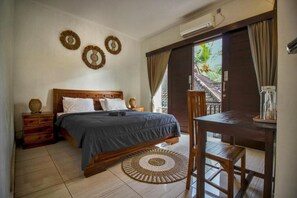 A bedroom with a bed, bedside tables, a desk, and a view of the outside. - ODA Guest House Ubud (Ubud)