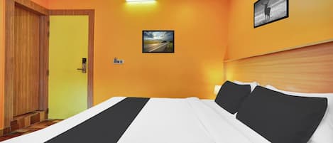 A hotel room with a bed, a door, a wall-mounted picture, and a ceiling light.