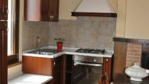 A kitchen with wooden cabinets, a gas stove, a sink, and a tiled backsplash. - "The Infinity" Apartment of Sibillini Montains (Montefortino)