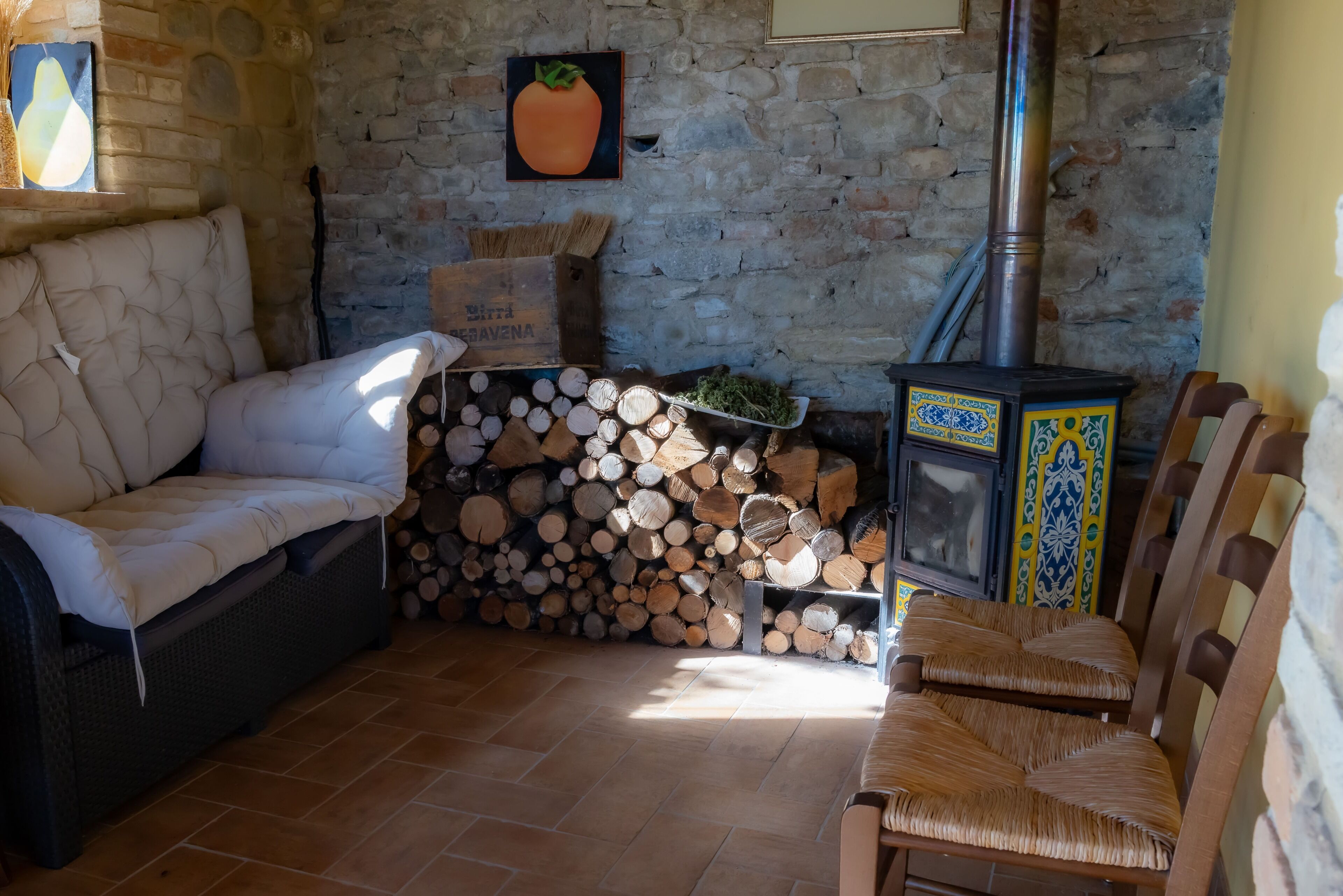 A cozy living room with a stone wall, a fireplace, a sofa, and a chair.