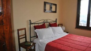 A single bed with a red quilt, a wooden chair, and a window with a view. - "The Infinity" Apartment of Sibillini Montains (Montefortino)