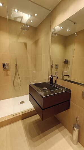 A modern bathroom with a glass-enclosed shower, a dark-toned sink, and a large mirror. - Loft, a designer apartment in a prime downtown location (Milano)