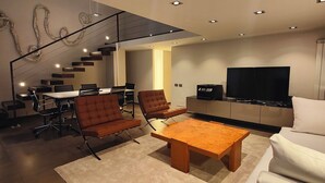 A modern living room with a sofa, coffee table, and a TV. There's a staircase leading to another level. - Loft, a designer apartment in a prime downtown location (Milano)