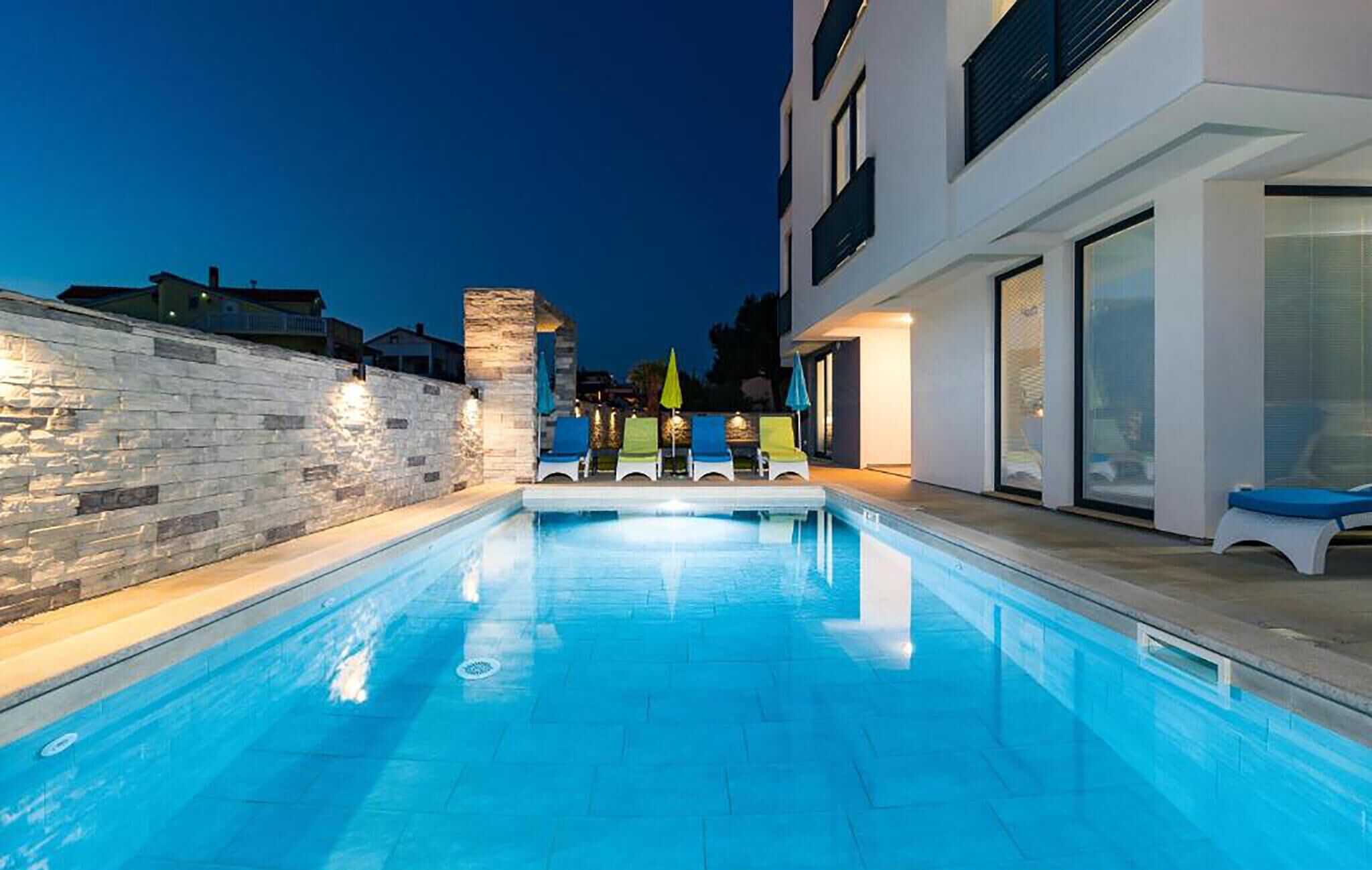 A swimming pool with lounge chairs and a stone wall.