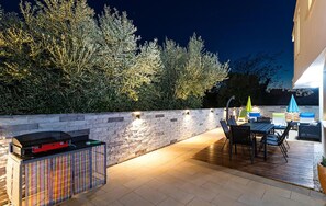 Ein Patio im Freien mit einer Steinwand, einem Grill und einer Sitzecke.