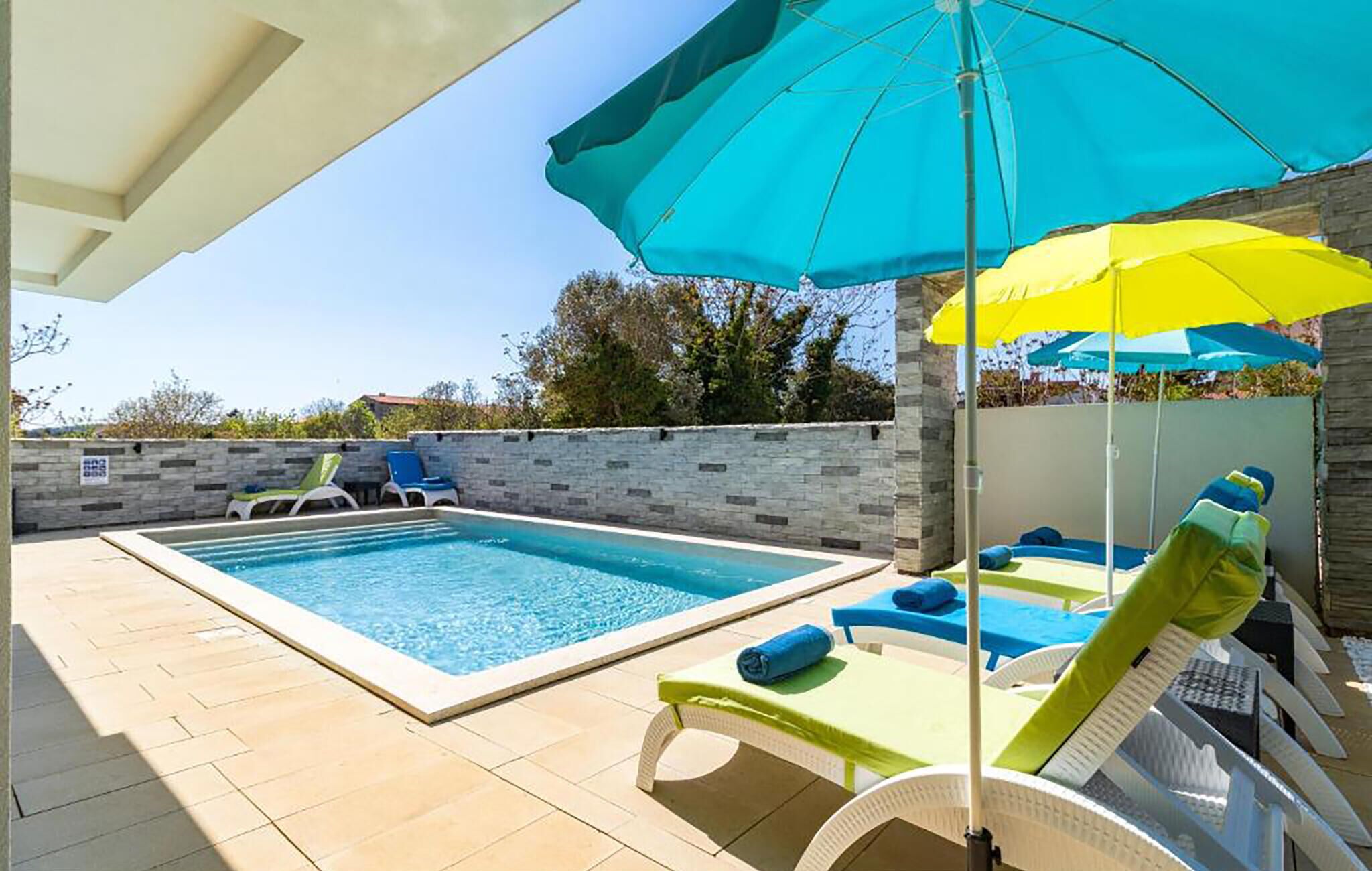 Uma piscina com espreguiçadeiras e guarda-sóis.