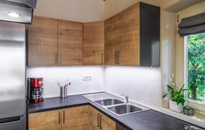A modern kitchen with wooden cabinets, a stainless steel sink, and a coffee maker. - Stunning home in Krnica (Krnica)