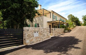 Ein zweistöckiges Haus mit Steinmauer und überdachter Veranda.