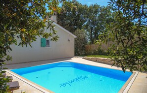Une piscine à l’eau d’un bleu cristallin, entourée d’une terrasse aménagée avec des chaises longues.