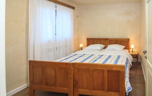 A double bed with a wooden headboard, two bedside lamps, and a striped bedspread. - Stunning home in Krnica (Krnica)