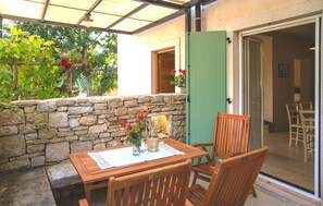 Eine Terrasse mit Steinmauer, Holztisch und Stühlen.