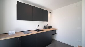 Eine moderne Küche mit schwarzer Arbeitsplatte, integriertem Spülbecken und einem Schrank darüber.