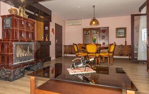 Ein Wohnzimmer mit Glastisch, Holzmöbeln, Kamin und Essbereich mit Stühlen.