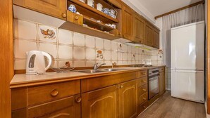 Una cocina con armarios de madera, un refrigerador blanco y salpicadero de azulejos.