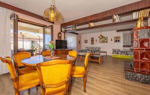 Ein geräumiger Wohnbereich mit Esstisch, Stühlen, einer Couch und einem Fernseher.