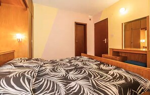 Ein Hotelzimmer mit Bett, Holzschrank, Tür und Spiegel.