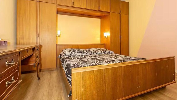 Un dormitorio con una cama de madera, un escritorio y un armario.