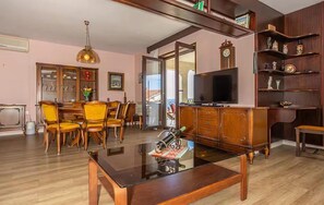A living room with a glass coffee table, wooden chairs, a television, and a bookshelf. - 1 bedroom awesome apartment in Crikvenica (Crikvenica)