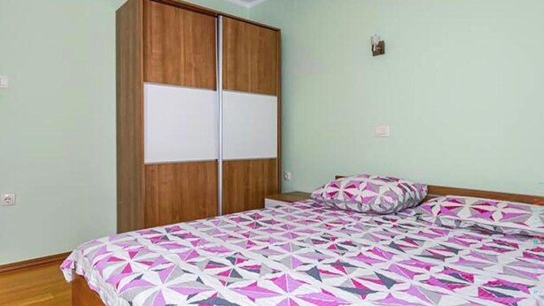 A bedroom with a bed, a wardrobe, and a wall-mounted light fixture. - Cozy apartment in Crikvenica with WiFi (Crikvenica)