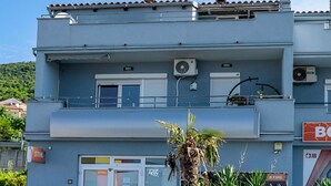 A two-story building with a balcony, air conditioning units, and a sign for a business. - Cozy apartment in Crikvenica with WiFi (Crikvenica)