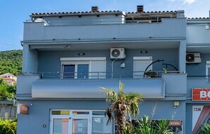 Ein zweistöckiges Gebäude mit Balkon, Klimaanlagen und einem Schild für ein Unternehmen.
