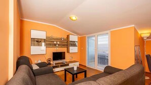 A living room with a sofa, a coffee table, a TV, and a sliding glass door leading to a balcony. - Cozy apartment in Crikvenica with WiFi (Crikvenica)