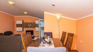 A dining area with a table set for four, a sofa, and a kitchen in the background. - Cozy apartment in Crikvenica with WiFi (Crikvenica)