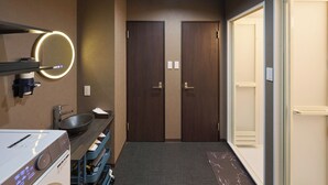 Un baño de hotel con lavamanos, espejo y dos puertas.