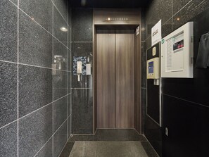 A modern elevator with a wooden door and a control panel on the wall. - Retrospect Stay Kannai 7 (Naka-ku, Yokohama-shi)