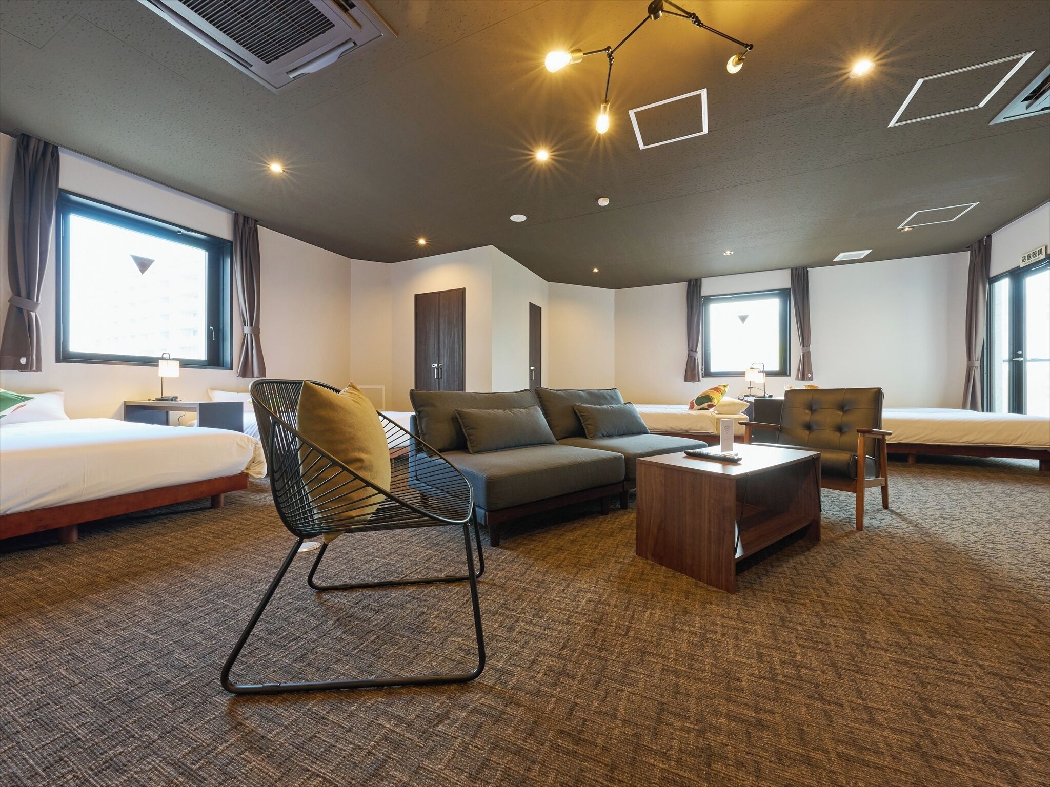 A hotel room with a bed, sofa, armchair, and a small wooden table.