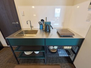 A compact kitchen with a stainless steel sink, a kettle, and a built-in induction cooktop. - Retrospect Stay Kannai 7 (Naka-ku, Yokohama-shi)