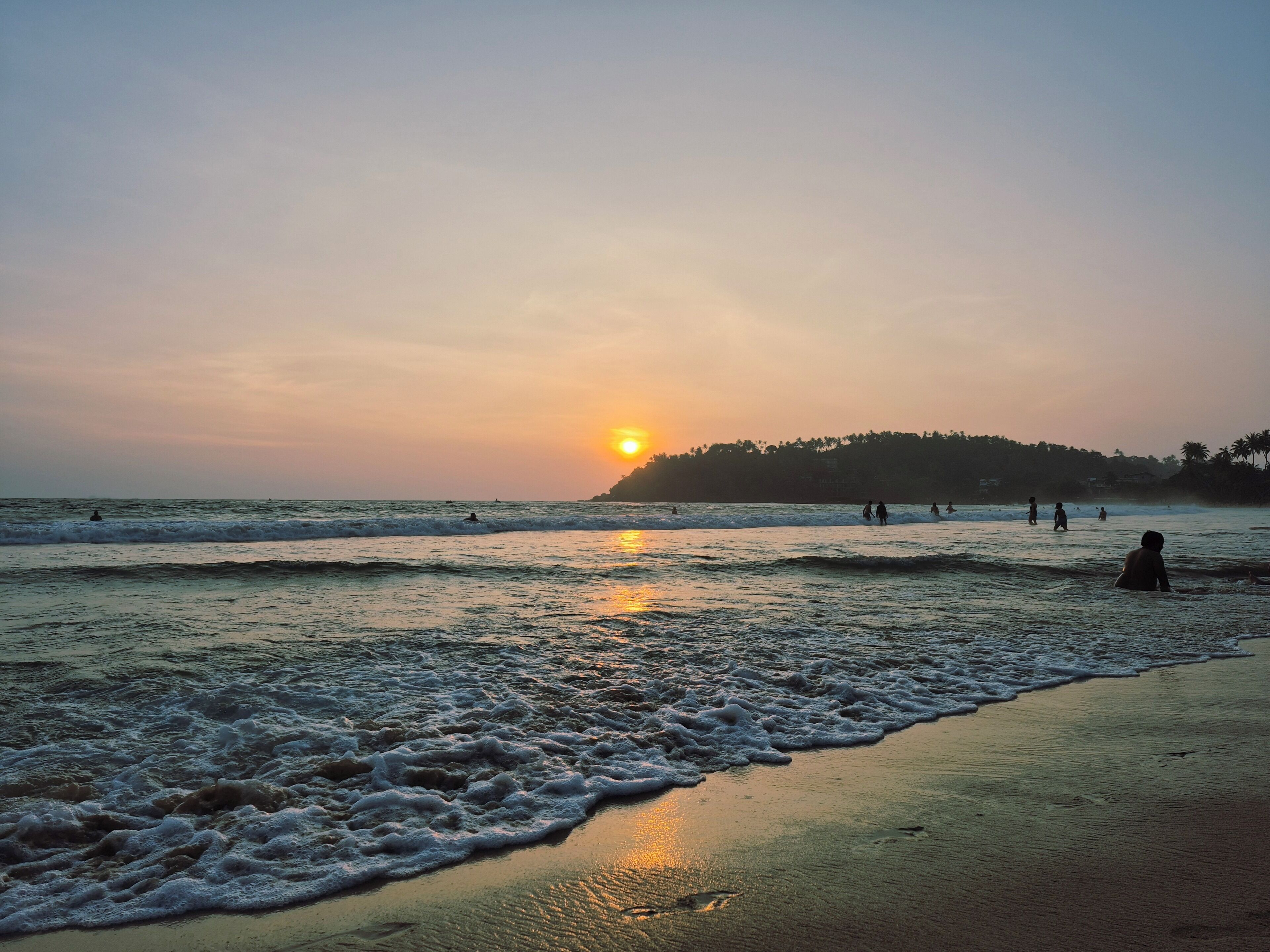 Une scène de plage avec des vagues et un coucher de soleil.