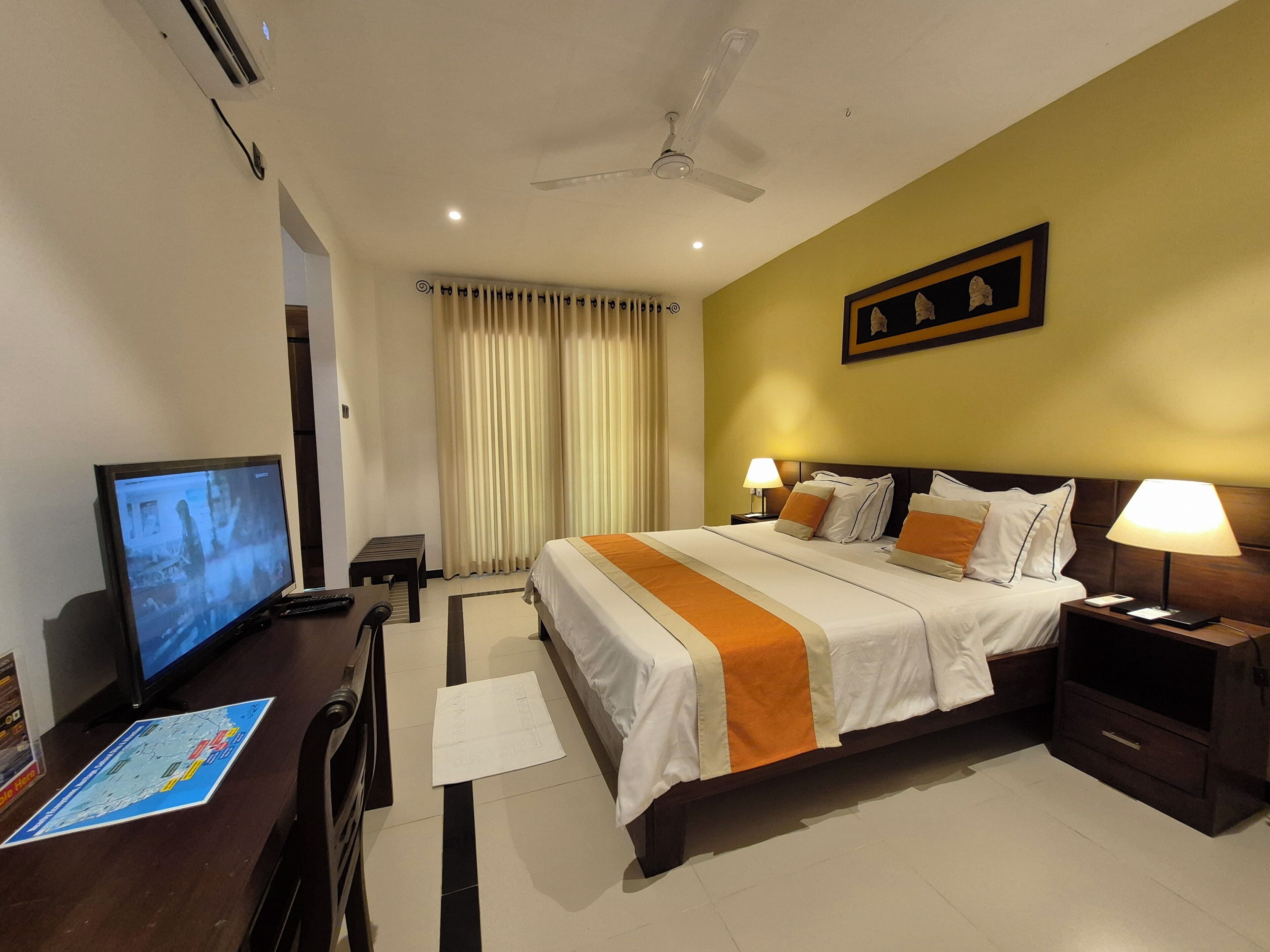 Habitación de hotel con cama, lámparas de noche, escritorio y televisión, además de un mapa en el suelo.